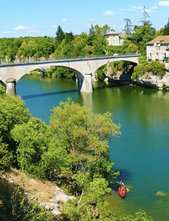 Photographie du pont en pierre de Ruoms avec des personnes en kayak